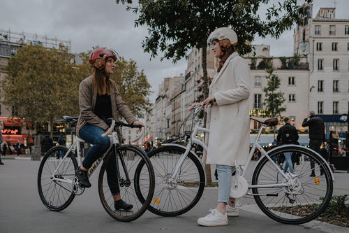 Deux cyclistes urbaines a velo dans une rue parisienne a la rentree