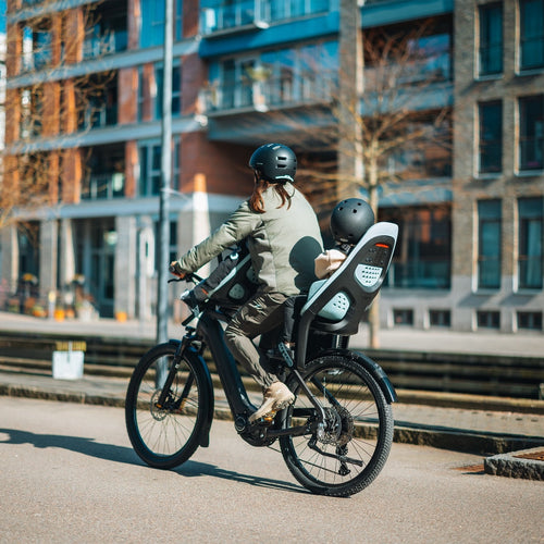 Parent et enfant sur un siege velo arriere pendant le trajet ecole en ville