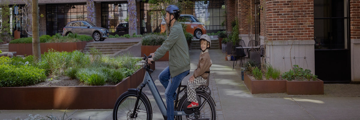 Père et enfant sur un siège vélo Qibbel Junior 6+ à vélo en ville
