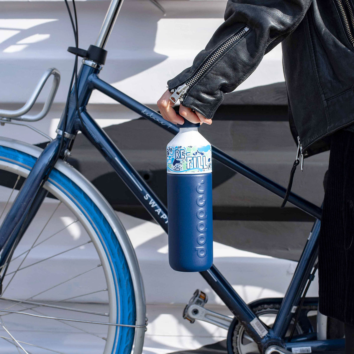 Cycliste urbain avec gourde isotherme Dopper sur son vélo en été
