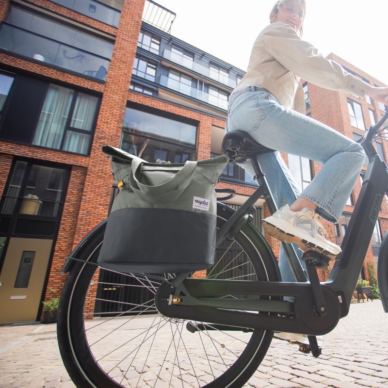 Cycliste avec une sacoche verte fixee sur le porte-bagages de son velo de ville